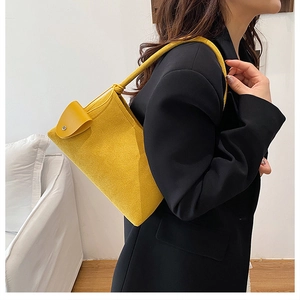 Chic yellow suede shoulder bag on black blazer model for elegant autumn office wear