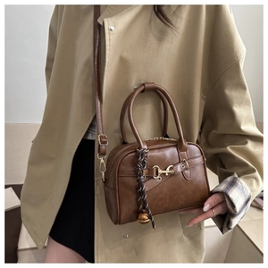 Brown Boston bag with horsebit detail and tassel charm styled with a beige trench coat