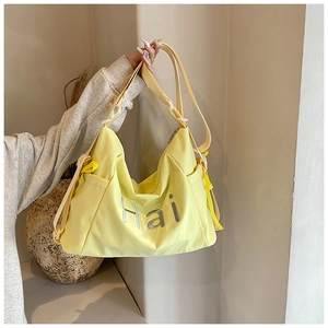 Détail du sac de voyage en nylon jaune montrant la poche latérale et la bandoulière