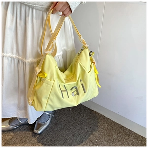 Détail du sac bandoulière en nylon jaune avec lettrage Hai et sangle réglable