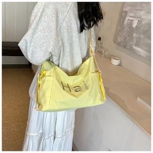 Detailed shot of large light yellow crossbody bag with letter print and side drawstrings
