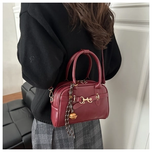 Detail of vintage burgundy Boston bag with gold horsebit hardware and bell charm