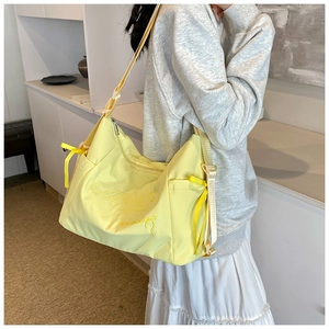 Gros plan du sac à dos en nylon jaune vif avec broderie artistique et poche latérale à cordon