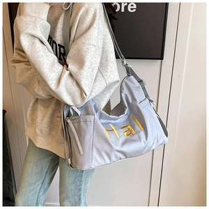 Détail du sac en nylon bleu clair avec broderie jaune et bandoulière grise réglable