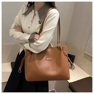 Detalle del bolso tote marrón con cordones ajustables y placa metálica frontal