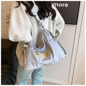 Detail of grey-blue nylon shoulder bag with yellow embroidery and drawstring side