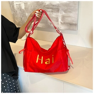 Détail du sac rouge en nylon avec lettrage Hai doré et bandoulière réglable