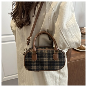 Detail of vintage plaid bowling bag with brown faux leather trim on a beige trench coat