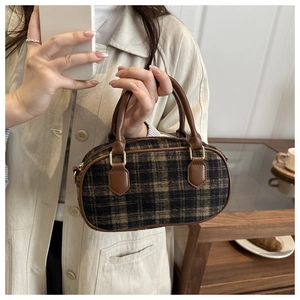 Retro plaid wool handbag with brown leather trim held by a model in a cozy setting