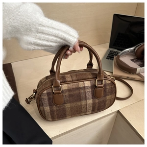 Close-up of retro plaid wool handbag with leather handle on an office desk