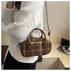Detailed close-up of brown plaid bowling bag with leather handles and gold hardware