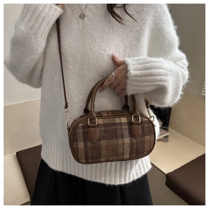 Brown plaid crossbody bowling bag shown on model wearing a white fuzzy sweater