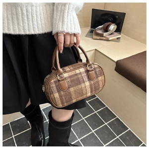 Close-up of retro brown plaid wool handbag with leather handles and metal hardware detail