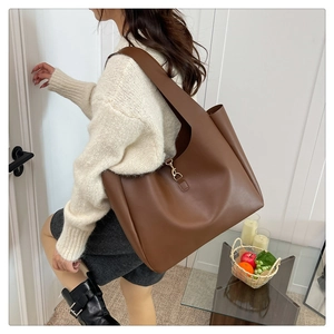Detail of deep brown tote bag featuring retro golden metal hook clasp and premium texture