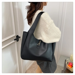 Detail of black matte PU leather tote bag with elegant gold metal hook on shoulder strap
