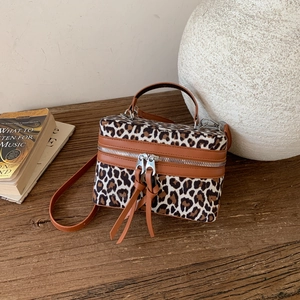 Vintage leopard print box handbag with leather trim and shoulder strap on wooden table