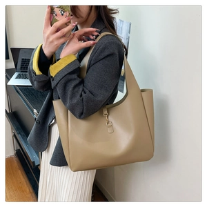 Detail view of khaki leather tote bag with wide strap and metal hook closure for daily use