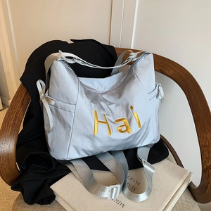 Sac fourre-tout en nylon argenté avec broderie Hai dorée sur chaise, style minimaliste