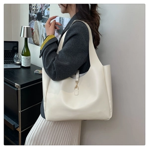 Model wearing cream white matte leather tote bag with elegant gold metal hook detail