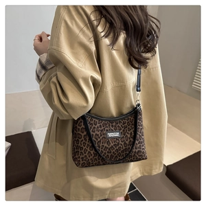 Detail of leopard print tote bag featuring fabric texture and black leather shoulder strap