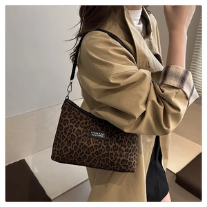 Dettaglio borsa shopper leopardata con etichetta del marchio e tracolla in pelle nera