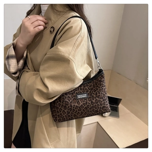 Detail of leopard print shoulder bag featuring leather strap and branded fashion label