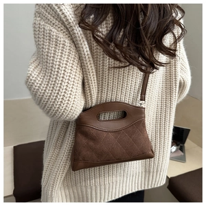Detail of coffee brown quilted suede handbag showing texture contrast and handle craftsmanship