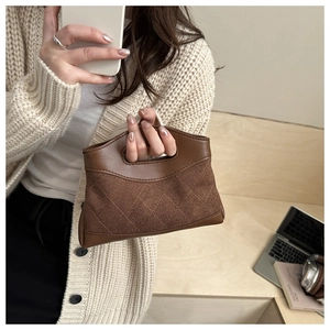 Detail of brown suede and leather patchwork handbag with quilted pattern and integrated handle