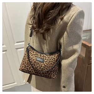 Macro detail of leopard print shoulder bag with black leather straps and adjustable hook