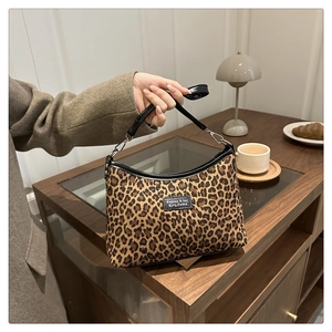 Detail of leopard print tote bag with black leather handles on a rustic wooden table
