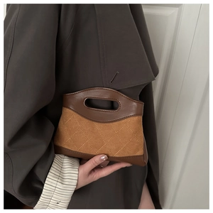 Detail of quilted suede shoulder bag with brown leather handle in a minimalist style