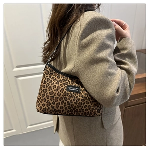 Dettaglio della borsa leopardata con patch logo e fibbia in metallo su un blazer beige