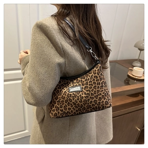 Detail of leopard print crossbody bag with fashion label and silver metal hardware