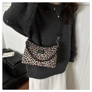 Detailed side view of leopard print shoulder bag with black strap and fabric label