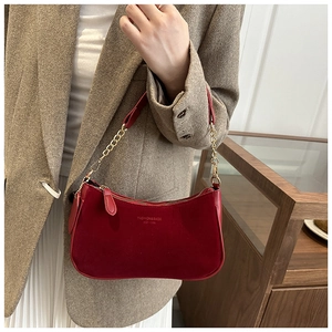 Détail du sac croissant en daim rouge avec chaîne dorée et logo de mode imprimé
