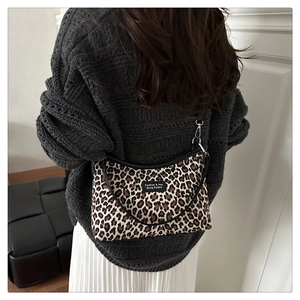 Detail of leopard print shoulder bag with silver metal hooks and black strap on model
