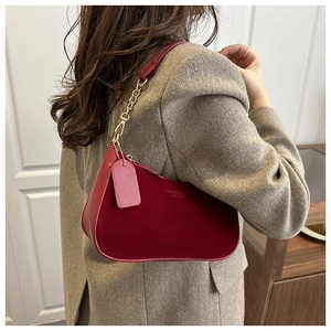 Détail du sac sous le bras en velours bordeaux avec chaîne dorée et bandoulière