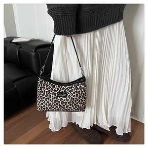 Detail of leopard print tote bag fabric with black leather trim and metal buckle