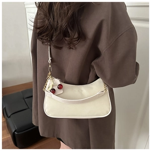 Detail of crescent shoulder bag in off-white with gold chain and cherry charm detail