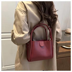 Close-up of wine red minimalist bucket bag with adjustable shoulder strap and matte finish