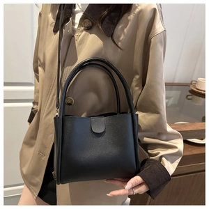 Close-up of black lychee grain bucket bag with vintage bronze hardware and crossbody strap