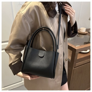 Minimalist black matte bucket bag with dual round handles and slim strap for daily styling