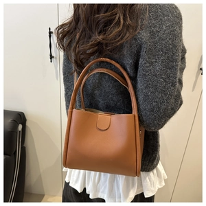 Brown faux leather bucket bag shown as a crossbody view on a person in home setting