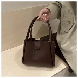 Close-up of a chocolate brown leather bucket bag with dual handles and elegant stitching