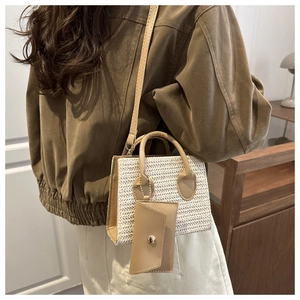 Detalle del bolso de paja trenzada con ribete de cuero sintético marrón y bolsa pequeña