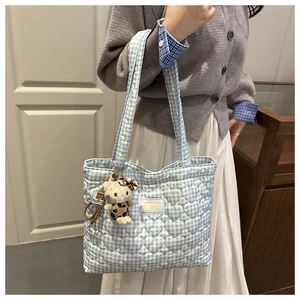 Detalle de textura acolchada de corazón en bolso tote de cuadros azul con dije de gato