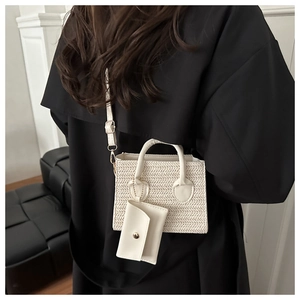 Detail view of a cream woven crossbody bag with a matching small leather coin pouch accessory