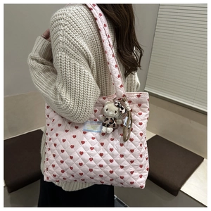 Detalle del bolso tote acolchado rosa con corazones rojos y un tierno colgante de peluche