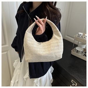 Détail de la texture tressée ondulée sur le sac à main hobo en paille crème