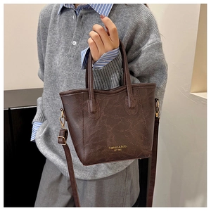 Close-up of retro brown litchi pattern leather bucket bag with gold fashion lettering